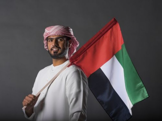 Middle Eastern man carrying the UAE Flag|