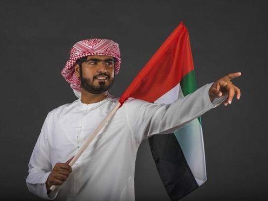 Middle Eastern man pointing and carrying the UAE flag