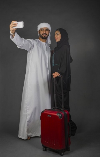 Middle Eastern man and Middle Eastern woman taking a selfie together|-