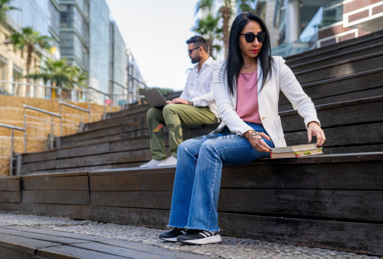 Woman Reading a Book and Man Working Outdoors in Amman’s Abdali Boulevard