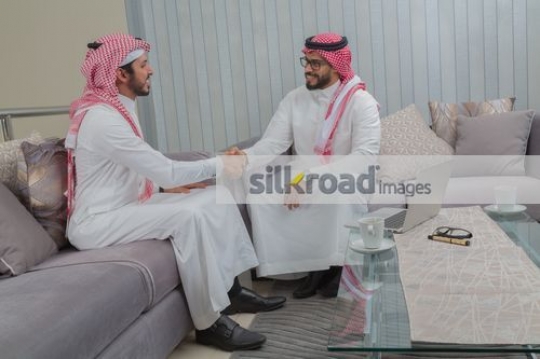 Arab Businessmen sitting on the couch shaking hands|